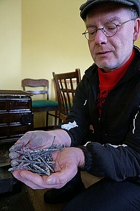 Also wird im Wohnzimmer geheizt. Voraus wäre allerdings der Ofen von den Überresten zuvor verbrannter Holzteile zu bereinigen.